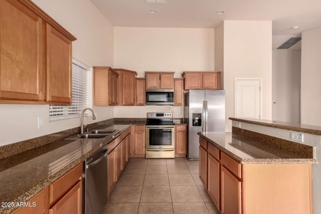 kitchen with sink, a high ceiling, stainless steel appliances, light tile patterned floors, and dark stone counters