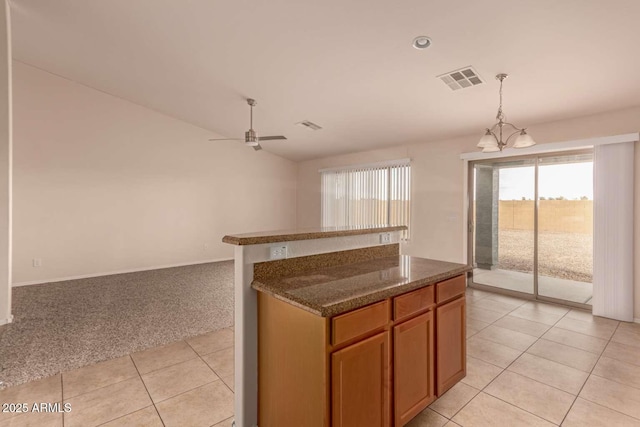 kitchen with light carpet, pendant lighting, ceiling fan with notable chandelier, and a center island