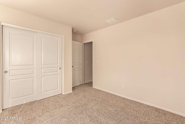 unfurnished bedroom with light colored carpet and a closet