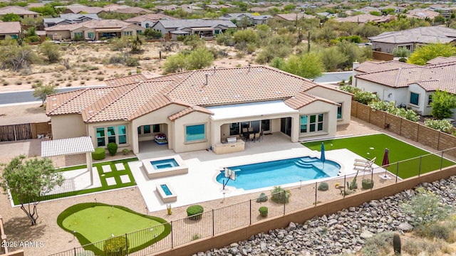rear view of property with a tile roof, a fenced backyard, a patio area, an in ground hot tub, and stucco siding