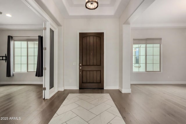 foyer featuring baseboards, dark wood-style floors, and a tray ceiling