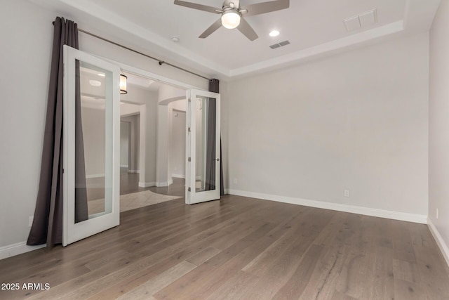 empty room featuring a ceiling fan, wood finished floors, and visible vents
