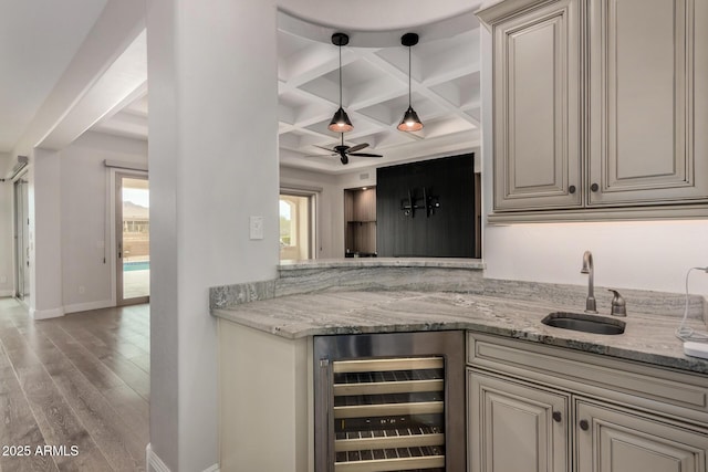 bar featuring beverage cooler, coffered ceiling, wood finished floors, a sink, and baseboards