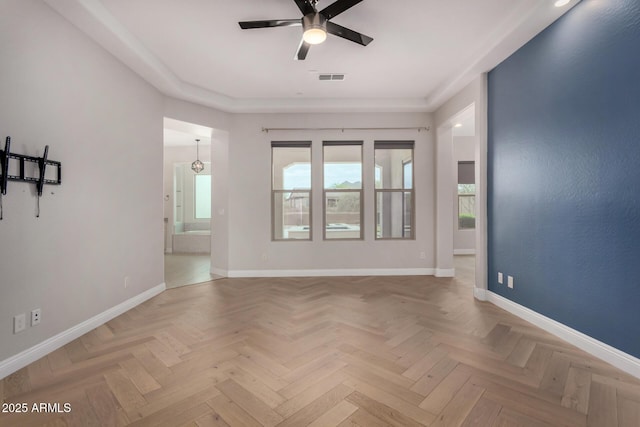 spare room with visible vents, a ceiling fan, and baseboards