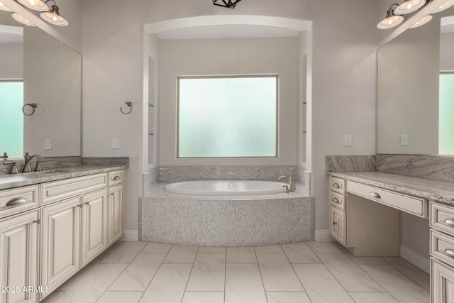bathroom with marble finish floor, a garden tub, and vanity