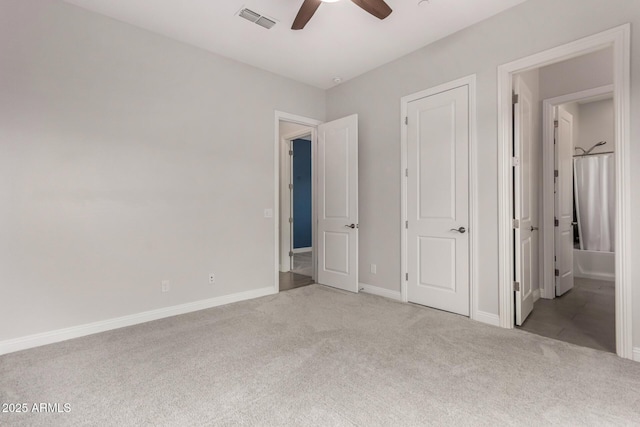 unfurnished bedroom featuring baseboards, visible vents, light colored carpet, a ceiling fan, and ensuite bath