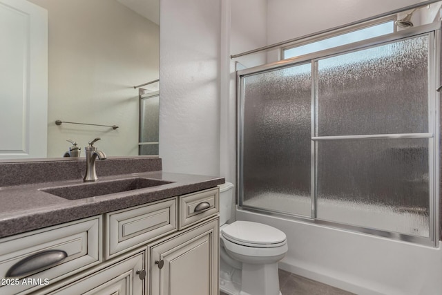 bathroom with tile patterned floors, vanity, shower / bath combination with glass door, and toilet