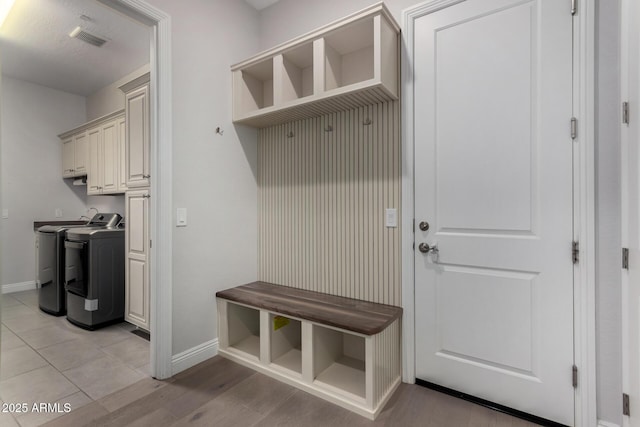 mudroom with washing machine and dryer, baseboards, visible vents, and light wood finished floors