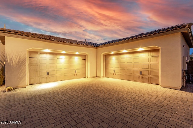 garage at dusk featuring driveway