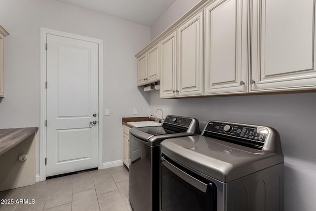laundry room with a sink, washing machine and dryer, baseboards, cabinet space, and light tile patterned floors