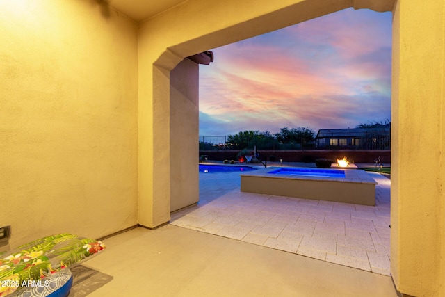 pool at dusk with an outdoor fire pit, a patio, and a fenced in pool