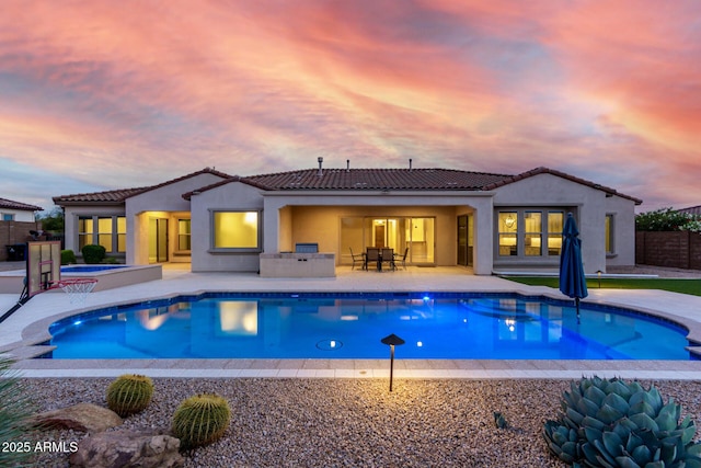 back of house featuring a fenced in pool, a tile roof, a patio, and stucco siding