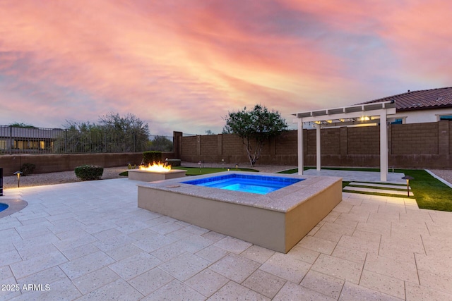 pool at dusk with a fire pit, a patio area, a fenced backyard, and an in ground hot tub