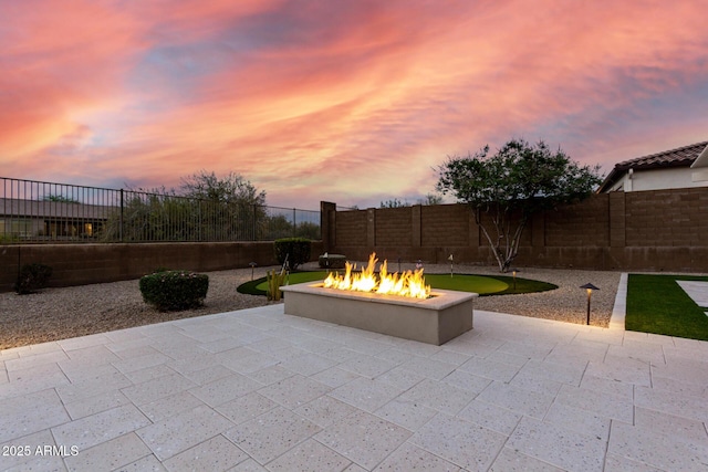 patio terrace at dusk with a fire pit and a fenced backyard