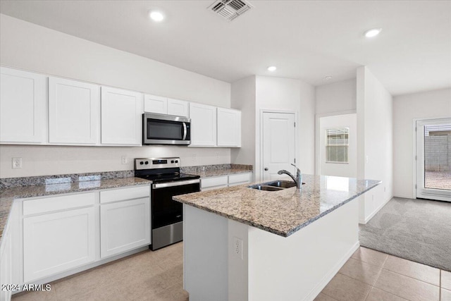 kitchen with appliances with stainless steel finishes, sink, white cabinetry, light carpet, and a kitchen island with sink