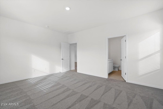 unfurnished bedroom featuring ensuite bathroom and light colored carpet