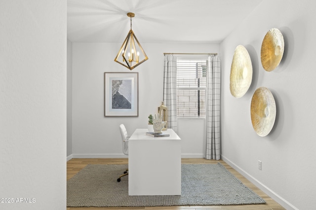 dining space featuring light wood-type flooring, an inviting chandelier, and baseboards