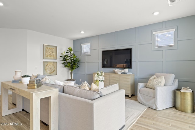 living area featuring wood finish floors, recessed lighting, visible vents, and a decorative wall