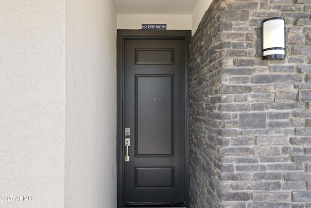 doorway to property featuring stone siding and stucco siding