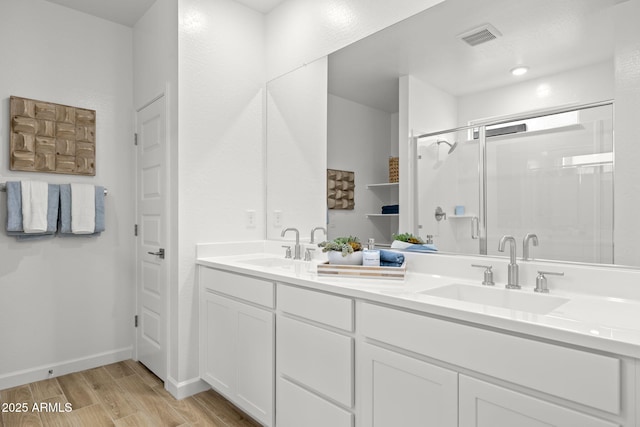 full bath featuring visible vents, a sink, a shower stall, and wood finished floors