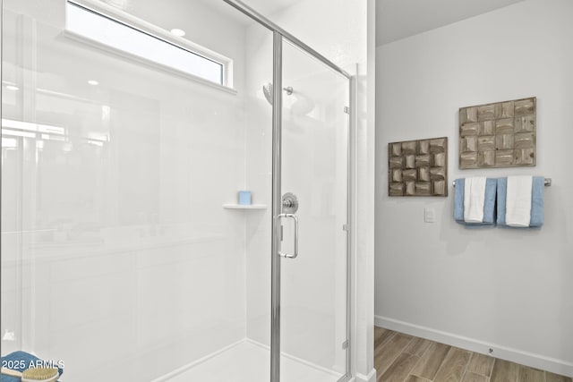 bathroom with a stall shower, baseboards, and wood finished floors