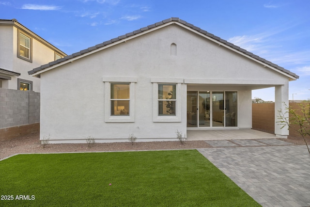 rear view of property featuring a patio, a yard, fence, and stucco siding