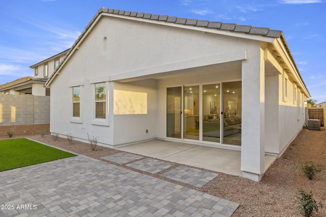 rear view of property featuring a patio, fence, and stucco siding