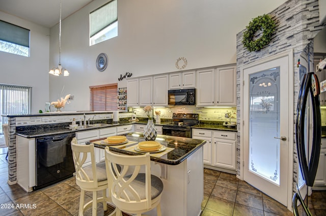 kitchen with a kitchen breakfast bar, black appliances, a high ceiling, and hanging light fixtures