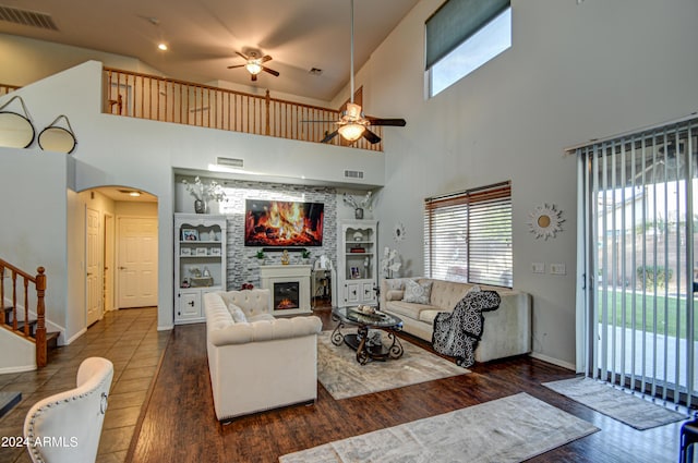 living room featuring built in features, ceiling fan, a high ceiling, and dark hardwood / wood-style floors