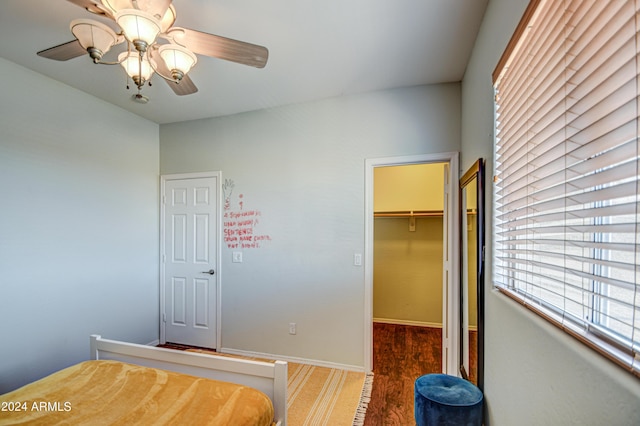 unfurnished bedroom with a closet, dark hardwood / wood-style floors, a spacious closet, and ceiling fan