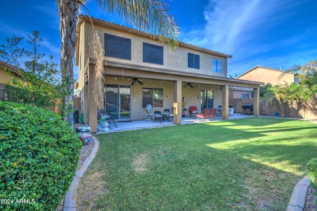 back of property with ceiling fan, a patio area, and a lawn