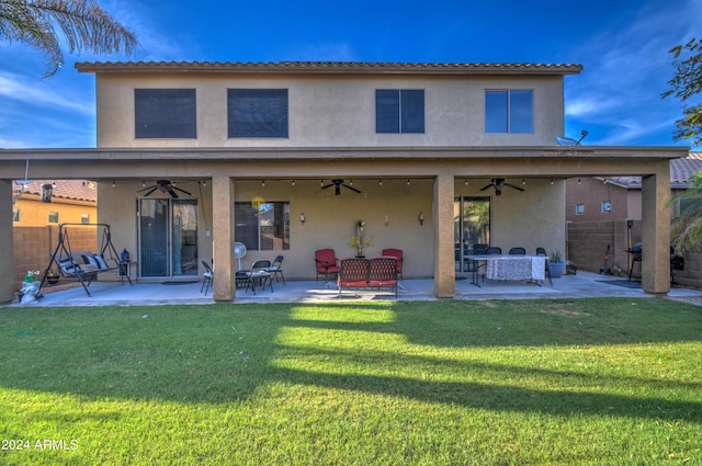 rear view of property featuring ceiling fan, a patio area, and a lawn