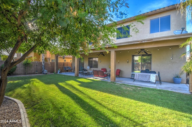 rear view of house featuring ceiling fan, a patio, and a yard