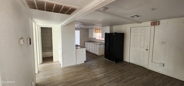 kitchen with white cabinets, a textured ceiling, dark hardwood / wood-style floors, and black refrigerator