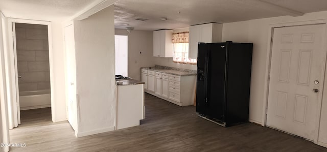 kitchen featuring dark hardwood / wood-style flooring, black refrigerator with ice dispenser, white cabinetry, and a textured ceiling