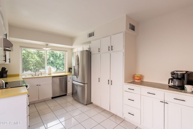 kitchen featuring appliances with stainless steel finishes, a sink, white cabinets, light countertops, and light tile patterned floors