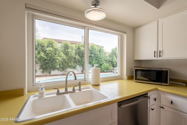 kitchen featuring stainless steel appliances, a sink, white cabinets, and light countertops