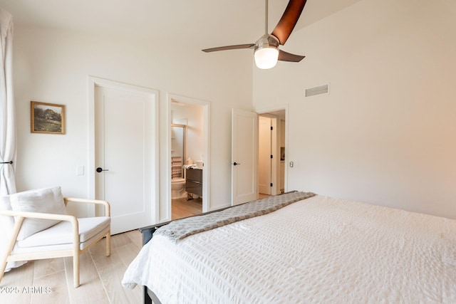 bedroom featuring light wood-type flooring, a ceiling fan, connected bathroom, and high vaulted ceiling