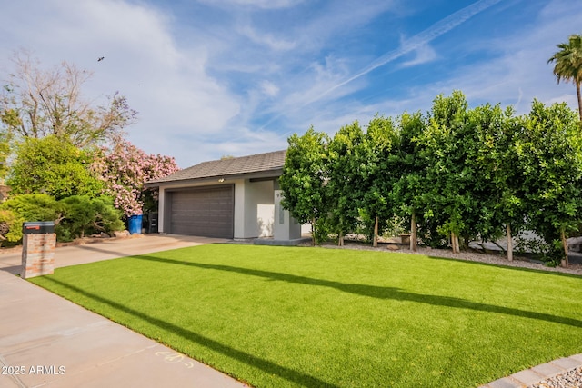 view of front of home with a front yard, concrete driveway, an attached garage, and stucco siding