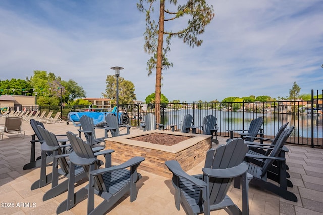 view of patio / terrace featuring a water view, an outdoor fire pit, and fence