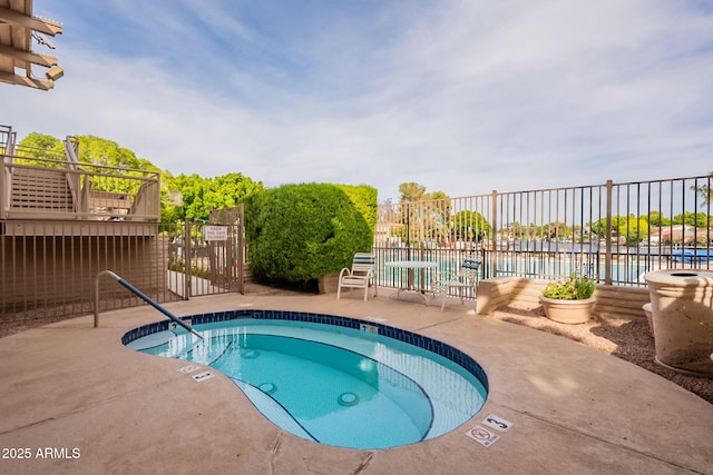 view of swimming pool featuring fence, a water view, and a patio area
