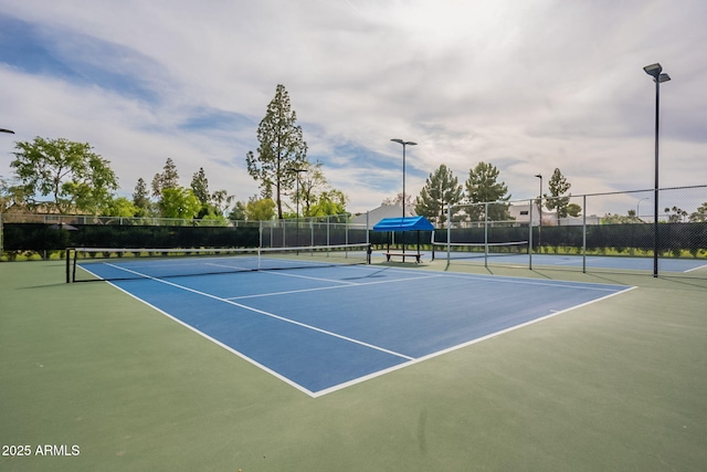view of tennis court with community basketball court and fence