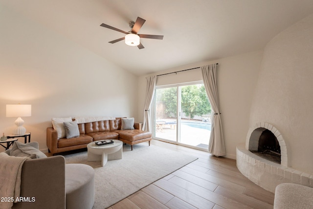 living area with wood finished floors, a ceiling fan, a brick fireplace, and high vaulted ceiling
