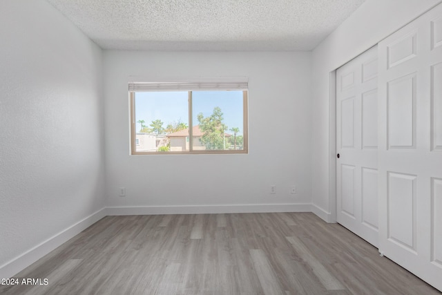 unfurnished bedroom with a closet, light hardwood / wood-style flooring, and a textured ceiling