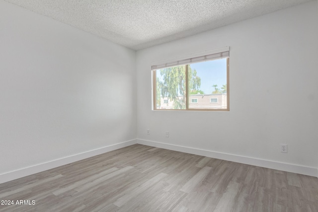 unfurnished room featuring light hardwood / wood-style floors and a textured ceiling