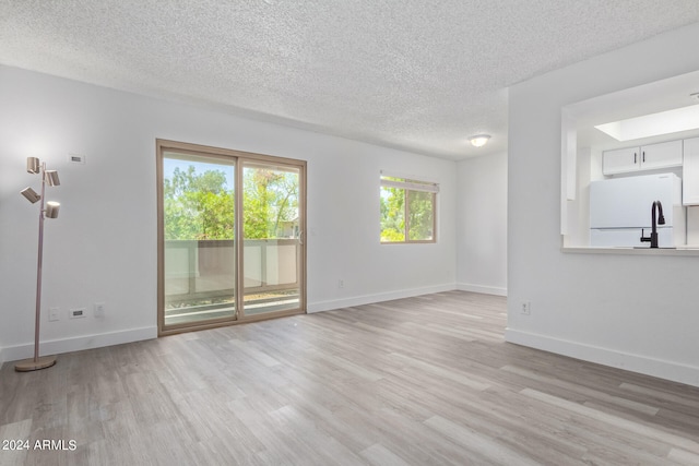 unfurnished living room featuring a textured ceiling and light hardwood / wood-style flooring