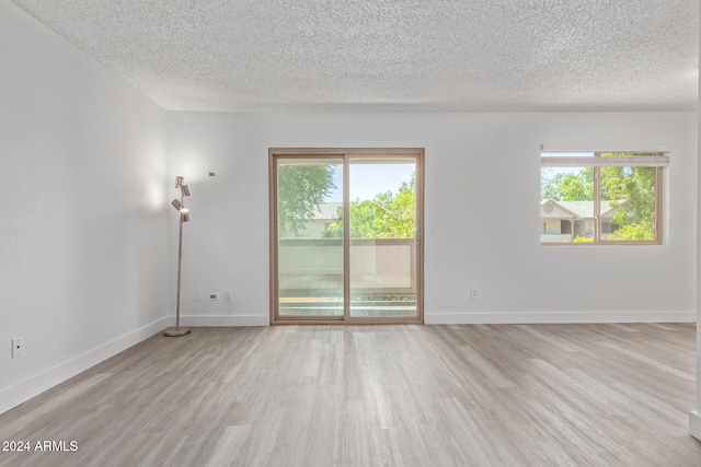 spare room with light hardwood / wood-style flooring, a wealth of natural light, and a textured ceiling