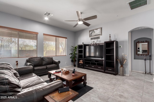 living room with arched walkways, visible vents, and baseboards