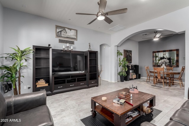 tiled living area featuring arched walkways and a ceiling fan