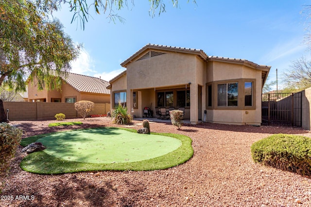 rear view of house with a fenced backyard, a patio, and stucco siding